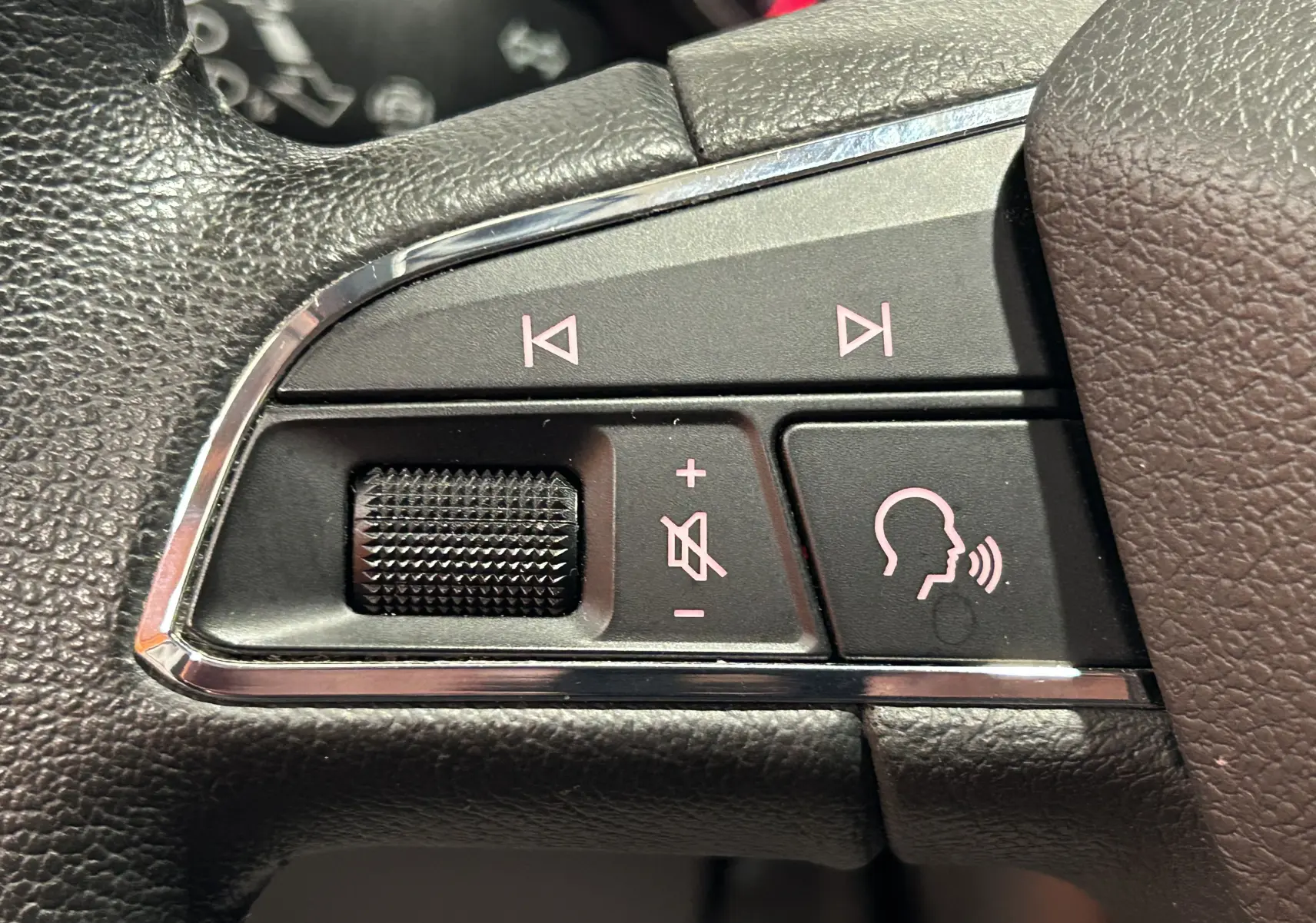 Gros plan sur les commandes vocales et volume au volant en cuir noir de la SEAT Ibiza blanche 2019.