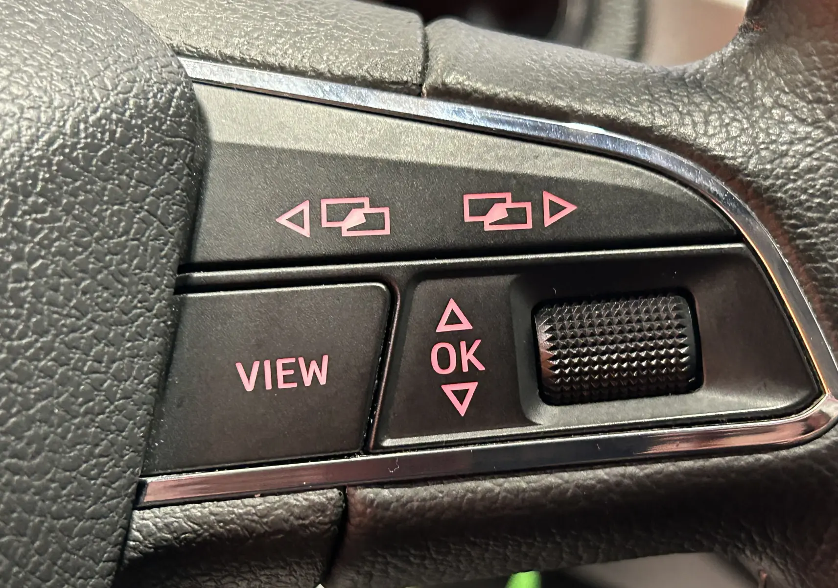 Gros plan sur les commandes du volant d'une SEAT Ibiza blanche 2019, boutons noirs avec inscriptions roses.