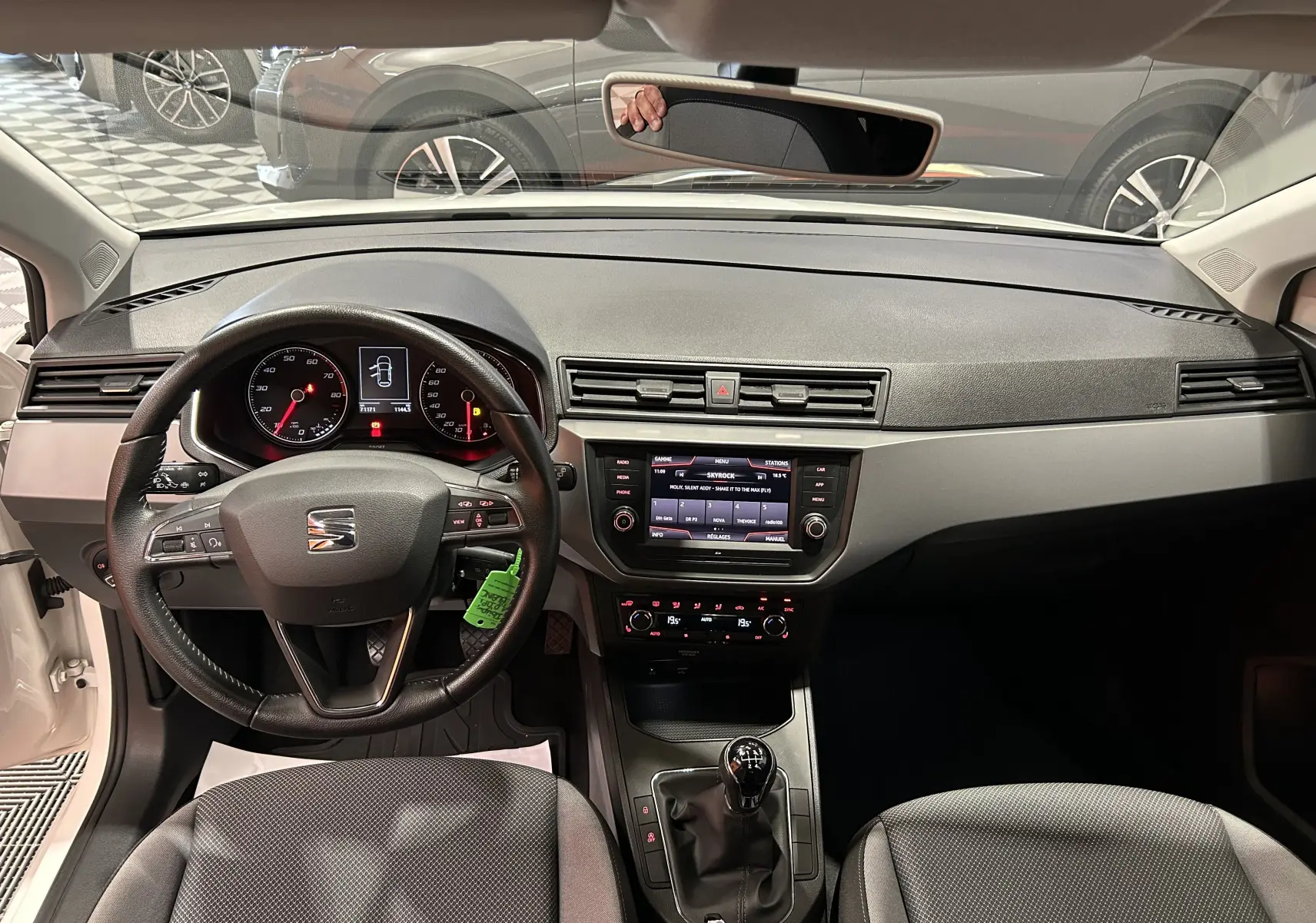 Vue intérieure frontale du tableau de bord et volant noir d'une SEAT Ibiza blanche 2019 avec boîte manuelle et sièges chauffants.
