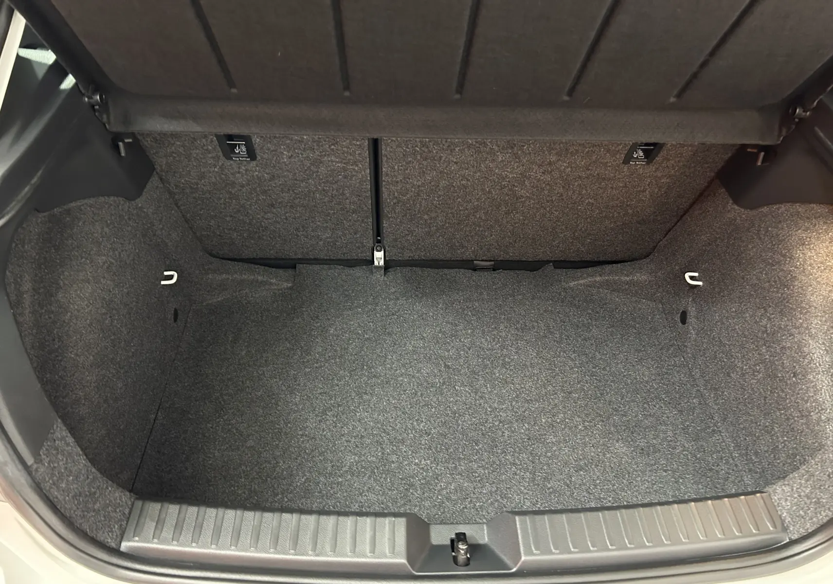 Coffre ouvert vu de face d'une SEAT Ibiza blanche 2019, montrant un espace de chargement vide et propre.