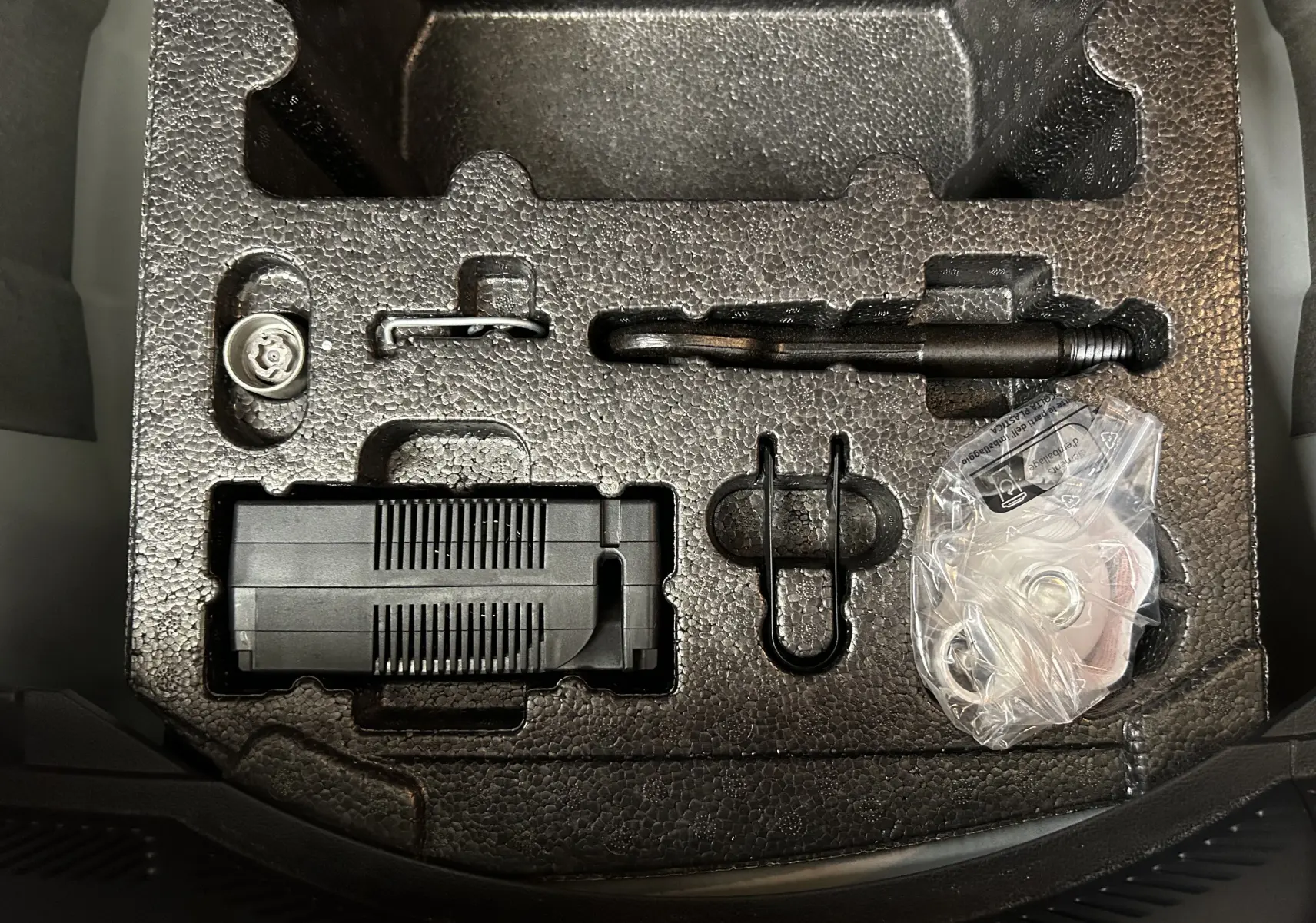 Vue en plongée sur le coffre d'une SEAT Ibiza blanche, montrant le rangement en mousse avec outils et compresseur intégrés.