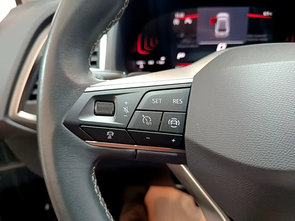 Gros plan sur le côté gauche du volant noir du SEAT Ateca 2022, avec commandes de régulateur de vitesse et assistance.