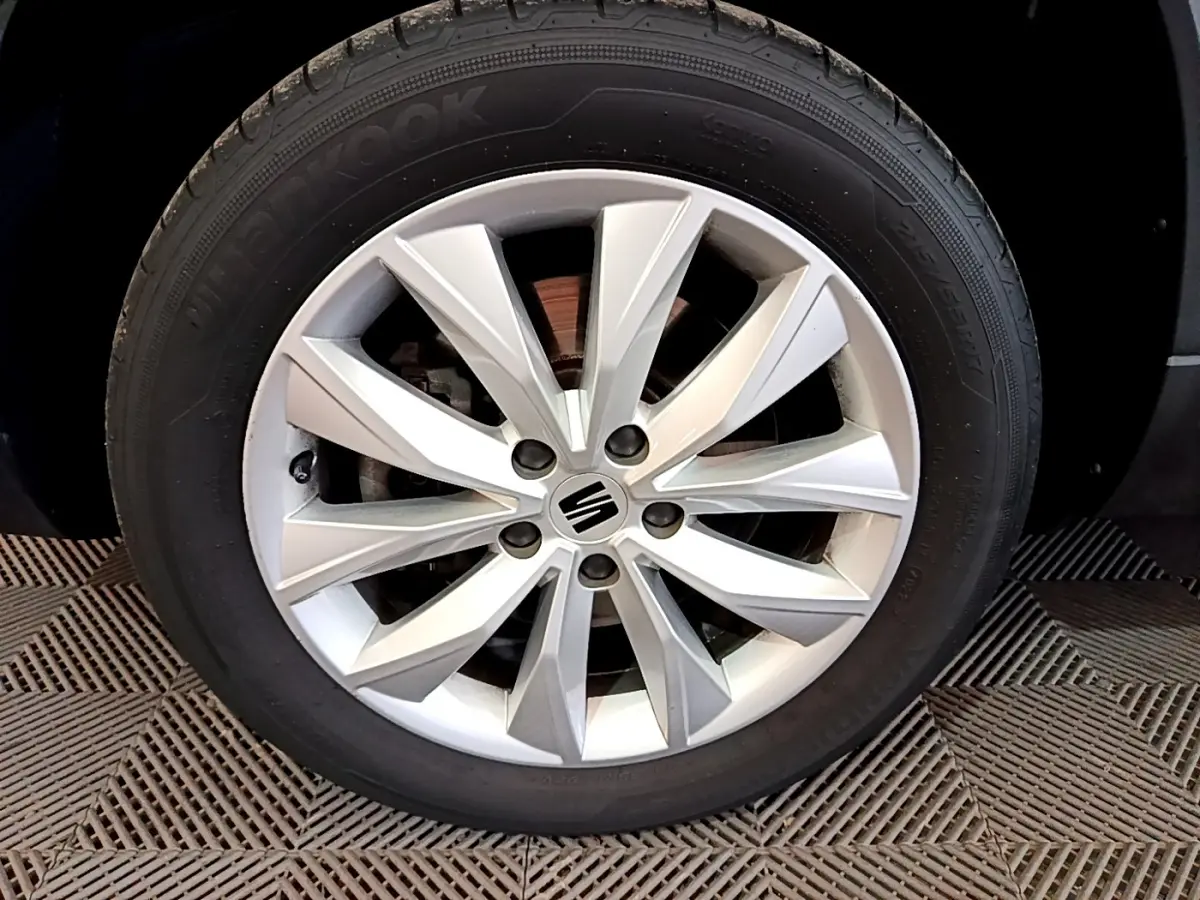 Gros plan sur la roue avant gauche avec jante alliage argentée du SEAT Ateca noir 2022.