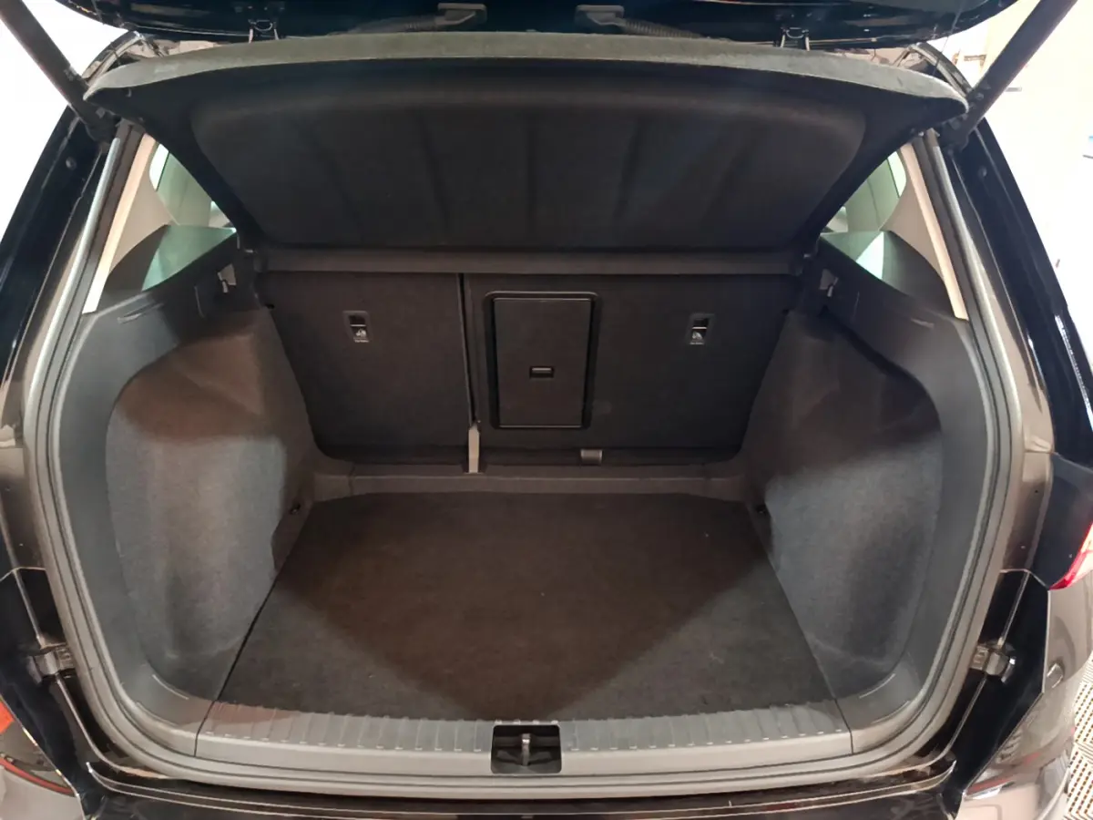 Coffre ouvert vu de l'arrière d'un SEAT Ateca noir 2022, espace de chargement spacieux et habillage sombre.