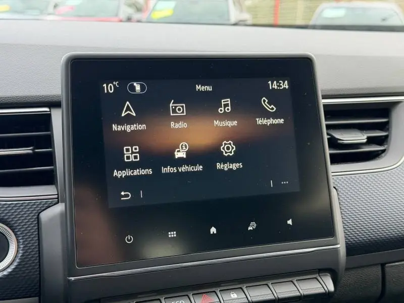 Écran tactile central du tableau de bord du Renault Arkana blanc, affichant le menu principal avec navigation et radio.