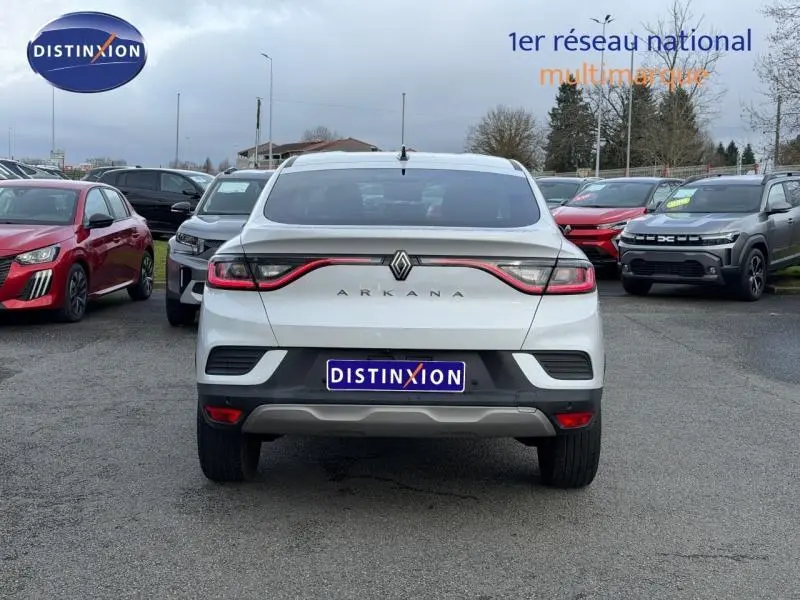 Vue arrière d'un Renault Arkana blanc 2025 avec feux reliés par un bandeau lumineux rouge, stationné en extérieur.