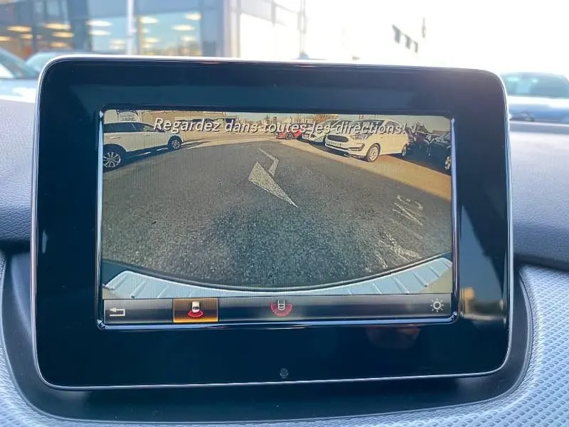 Écran de caméra de recul dans une Mercedes Classe B 180 d gris foncé métal, vue arrière du véhicule en stationnement.