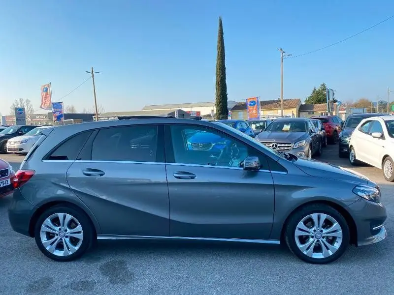 Vue latérale droite d'une Mercedes Classe B 180 d gris foncé métallisé, avec jantes alliage et lignes de carrosserie marquées.
