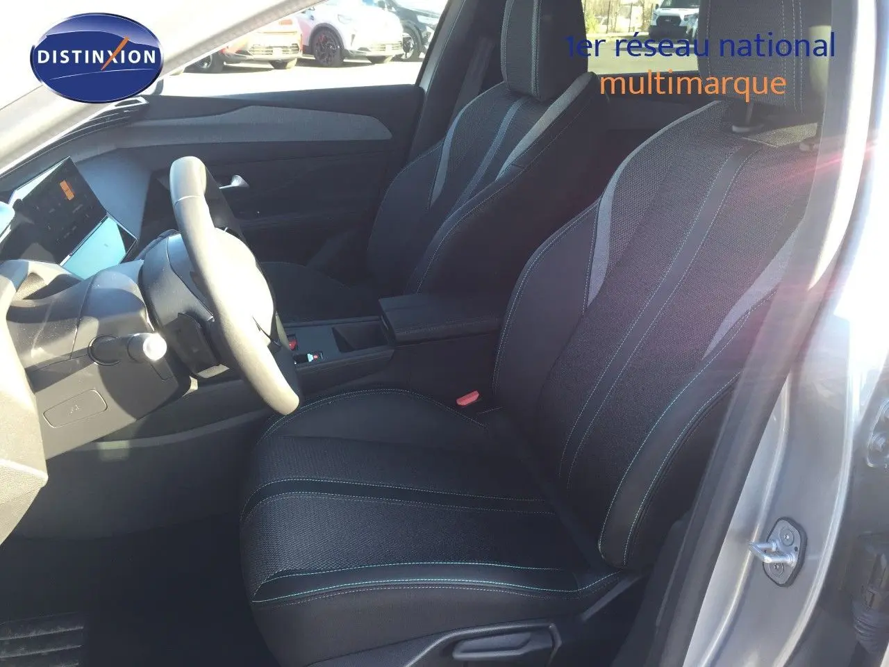 Vue intérieure côté conducteur de la Peugeot 308 gris Artense 2025, sièges en tissu noir avec surpiqûres contrastées.