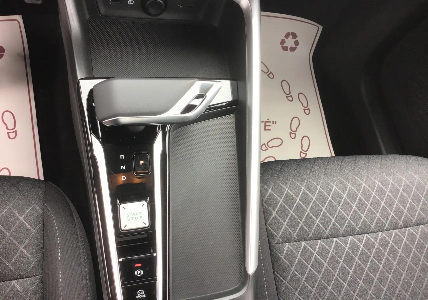 Vue plongeante sur la console centrale du MG ZS Cosmic Silver, montrant levier de boîte auto et sièges tissu noir.