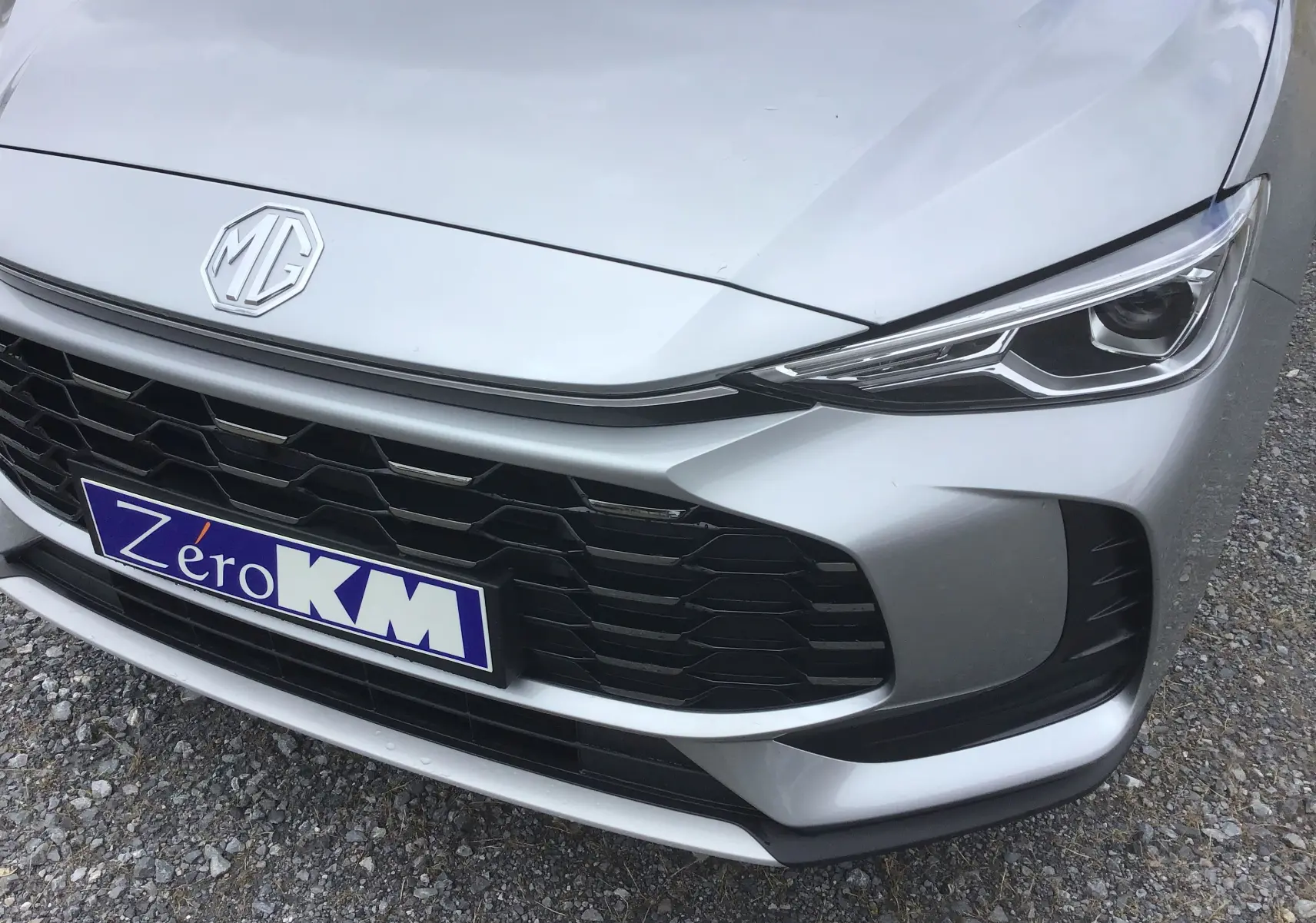Gros plan sur l'avant droit du MG ZS Cosmic Silver avec calandre noire et phares LED fins.