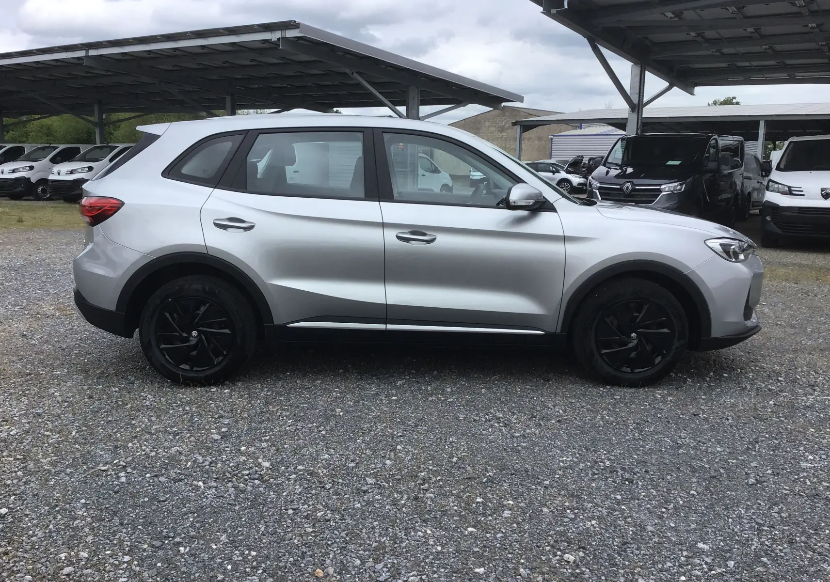 Vue de profil côté gauche du MG ZS Cosmic Silver avec jantes noires et détails noirs sur les bas de caisse.