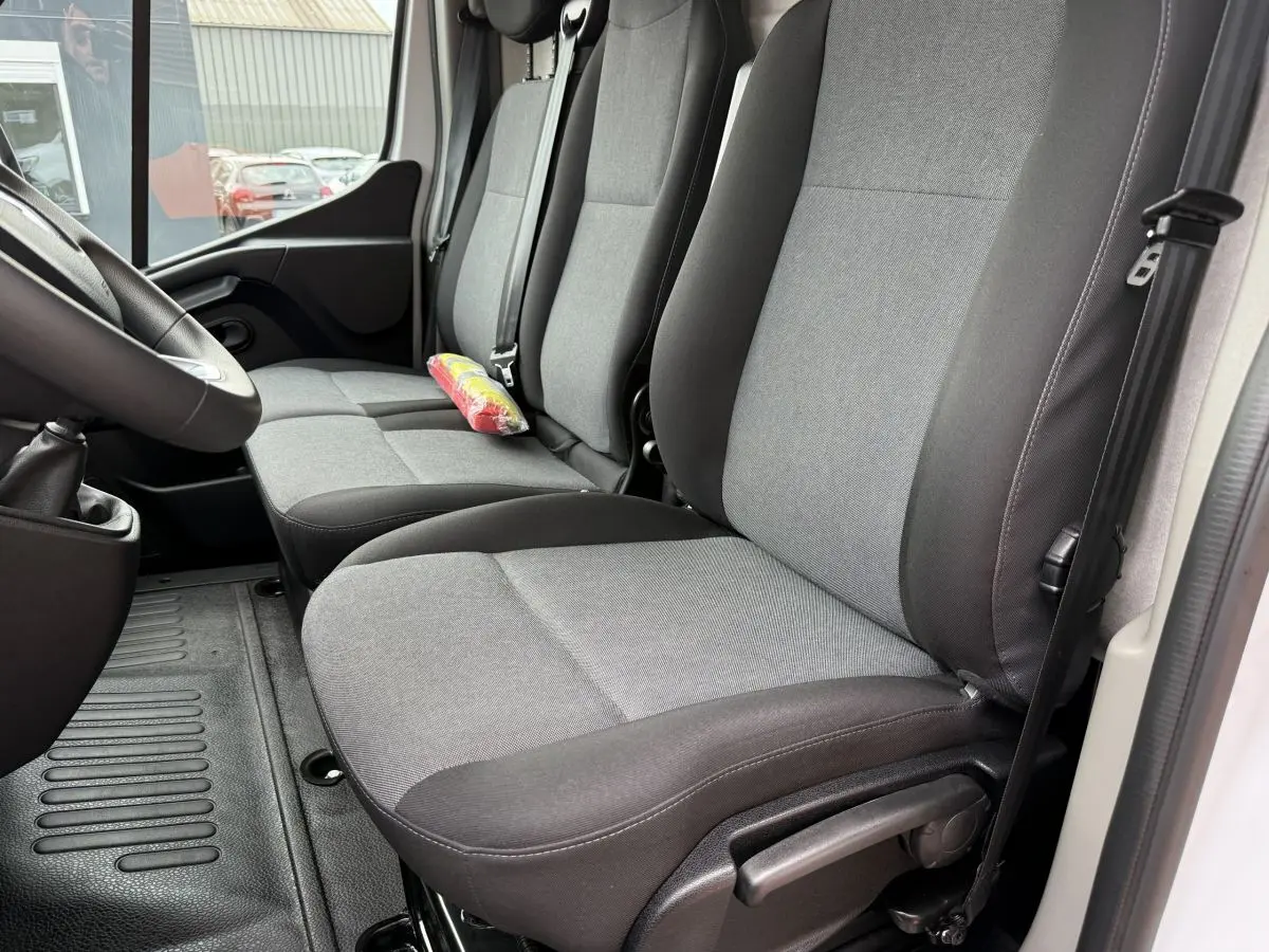 Vue intérieure côté conducteur du Renault Master blanc 2024, montrant les sièges tissu gris et noir et la ceinture de sécurité.