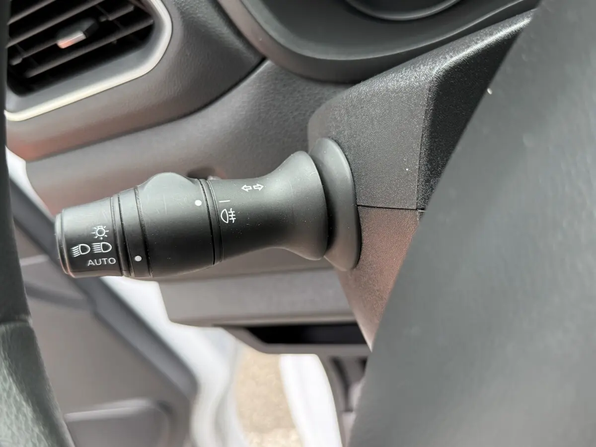 Gros plan sur la manette de commande des phares et clignotants du tableau de bord intérieur du Renault Master blanc.