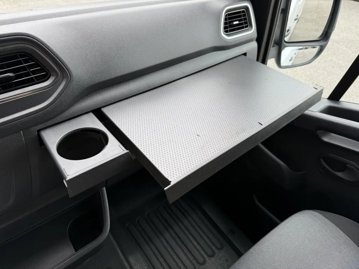 Vue intérieure côté passager du Renault Master blanc 2024, mettant en valeur la tablette coulissante et porte-gobelet intégré.