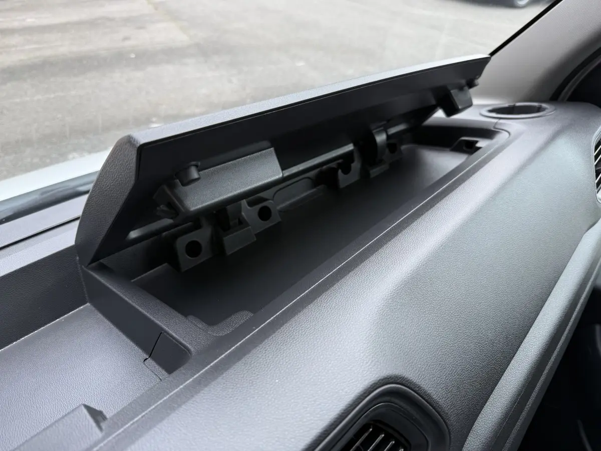 Vue rapprochée du rangement supérieur ouvert sur le tableau de bord gris du Renault Master blanc, côté passager.