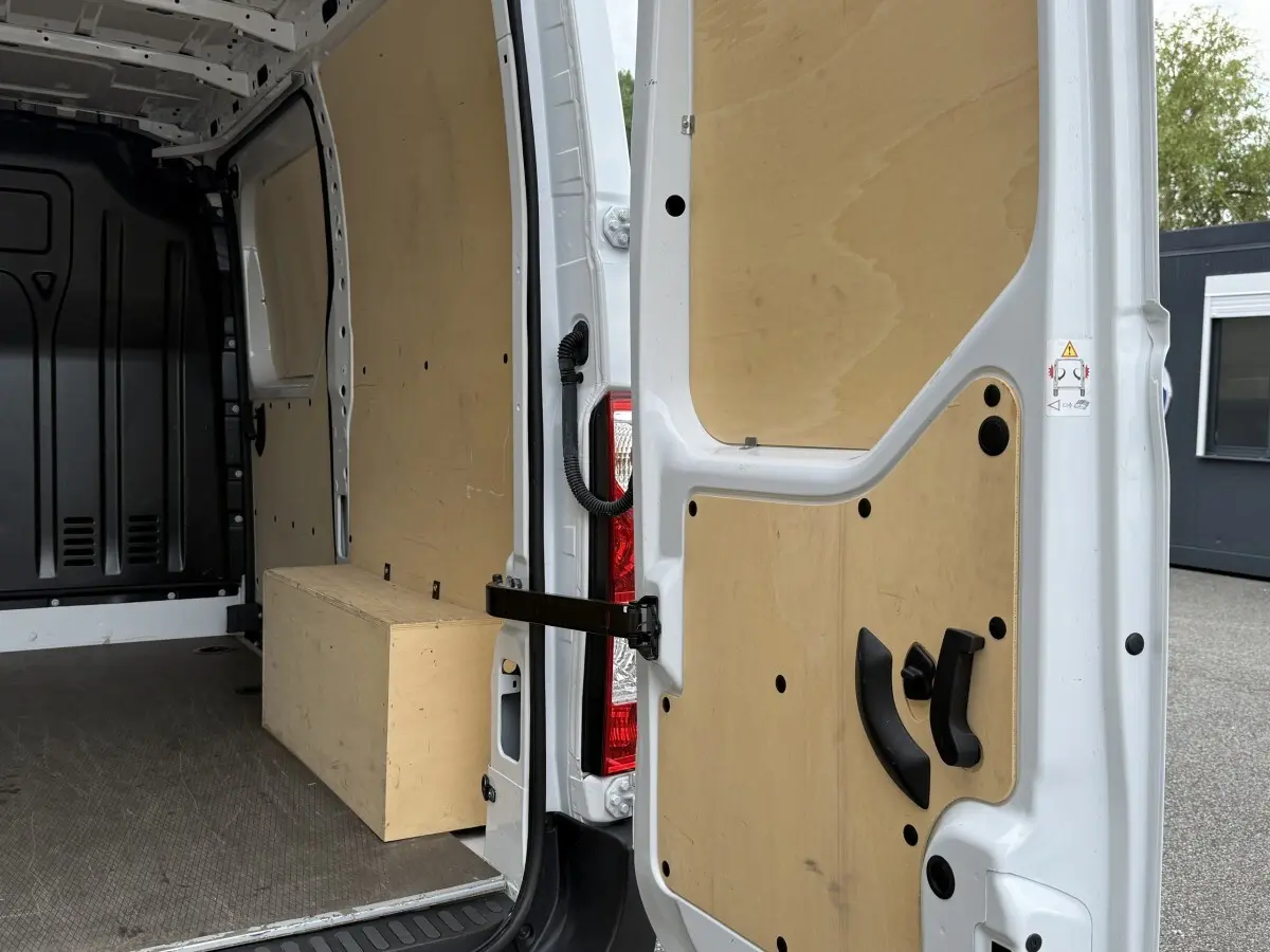 Vue intérieure arrière du Renault Master blanc 2024, montrant la cloison et les portes arrière ouvertes avec habillage bois.