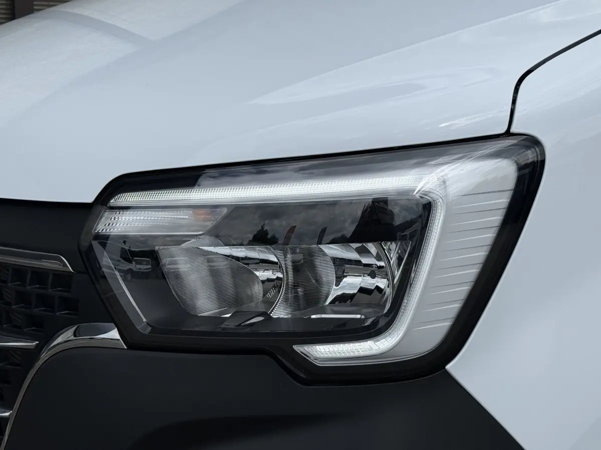 Gros plan sur le phare avant droit du Renault Master blanc 2024, mettant en valeur son design moderne et ses LED.