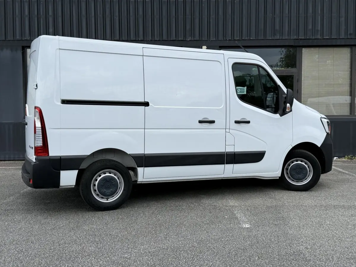 Vue de profil côté droit du Renault Master blanc avec jantes acier et bandeau noir sur porte latérale.