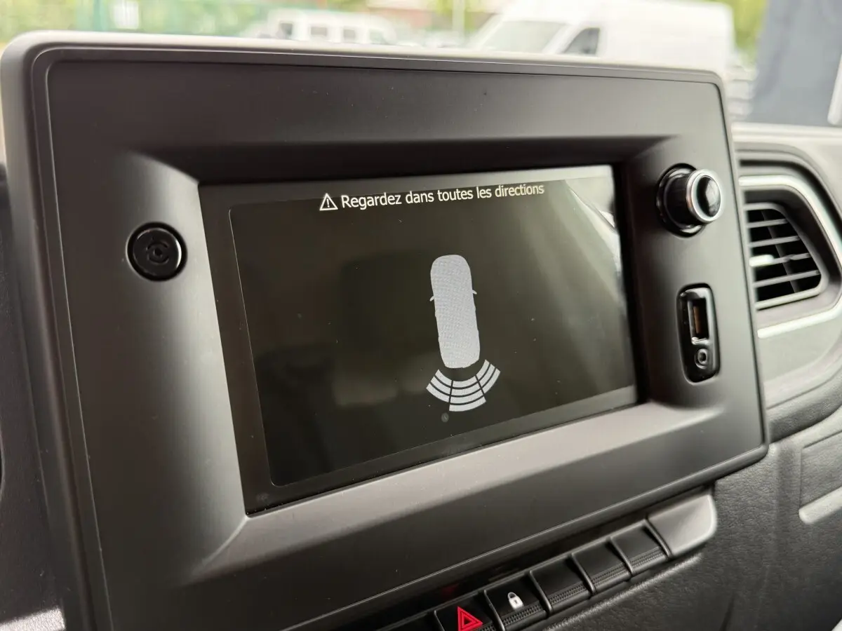 Écran tactile central du tableau de bord du Renault Master blanc 2024 affichant l'aide au stationnement arrière.