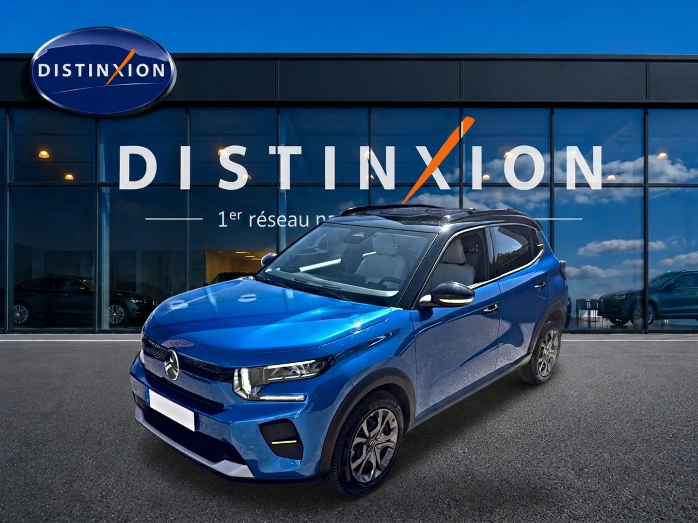 SUV Citroën C3 bleu en 3/4 avant droit, avec toit noir et jantes alliage, devant une vitrine Distinxion.