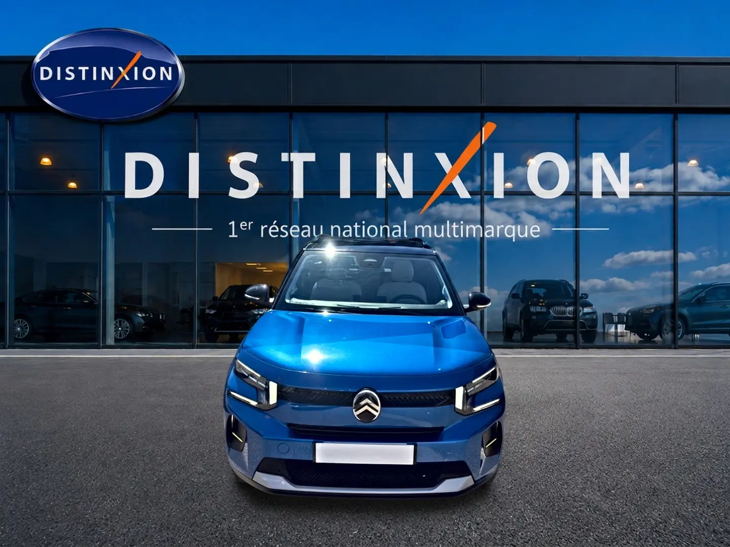 Citroën C3 bleu vue de face, avec calandre distinctive et phares LED, devant une vitrine Distinxion.