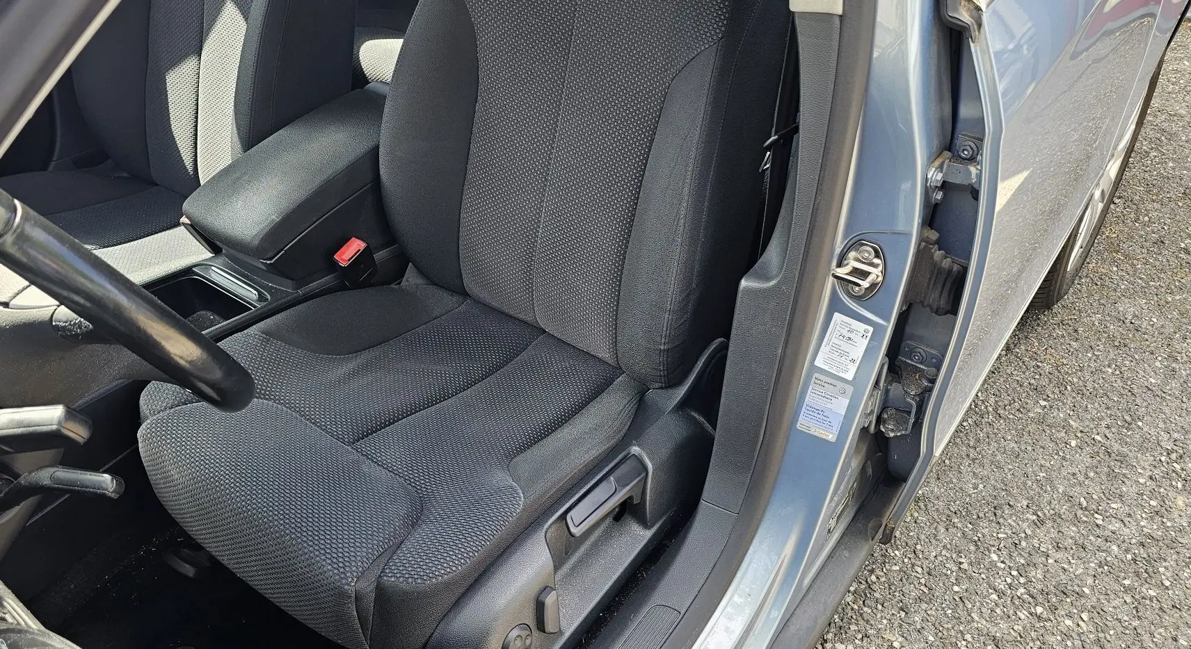 Vue rapprochée du siège conducteur noir et de l'encadrement bleu d'une Volkswagen Passat 2009 avec portière ouverte côté gauche.