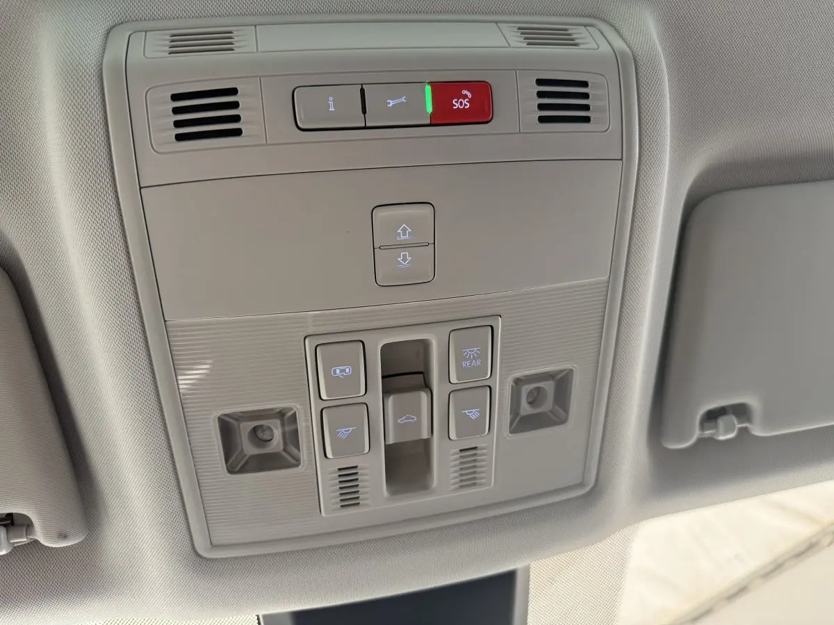 Vue en contre-plongée du panneau de commandes au plafond du SEAT Ateca gris clair 2023 avec bouton SOS illuminé rouge.