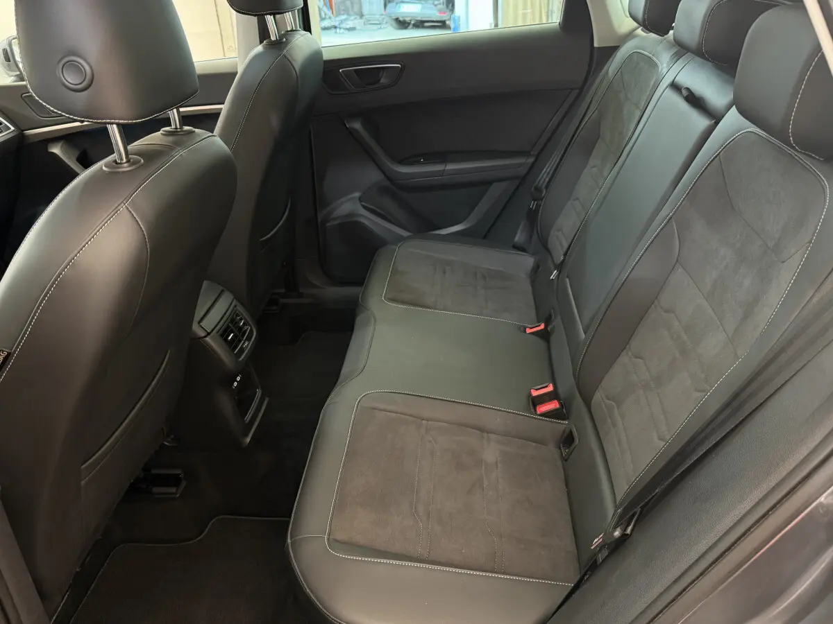 Vue intérieure côté droit des sièges arrière en cuir noir du SEAT Ateca gris clair 2023 avec appuis-tête et ceintures visibles.