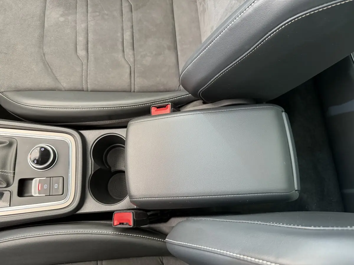 Vue plongeante sur la console centrale noire et les sièges gris clair du SEAT Ateca 2.0 TDI 2023 avec accoudoir fermé.
