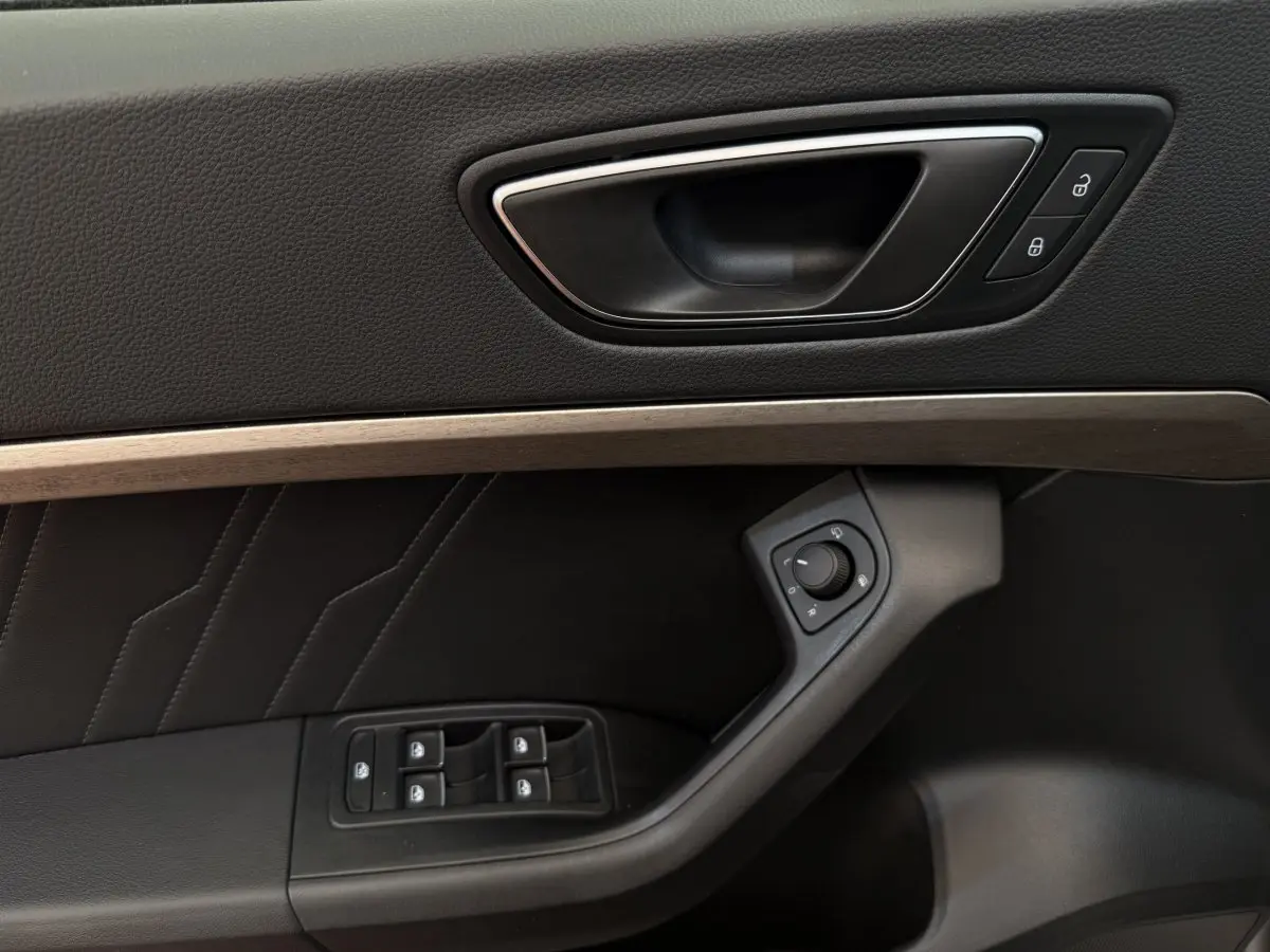 Détail de la porte côté conducteur du SEAT Ateca gris clair 2023 avec commandes électriques et habillage noir.