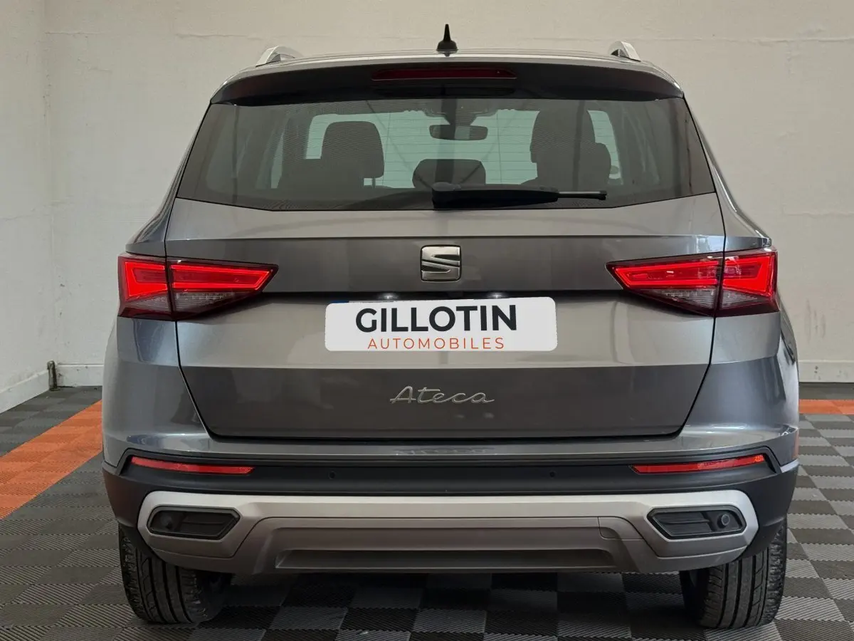 Vue arrière d'un SEAT Ateca gris clair 2023 avec feux LED et double sortie d'échappement intégrée.