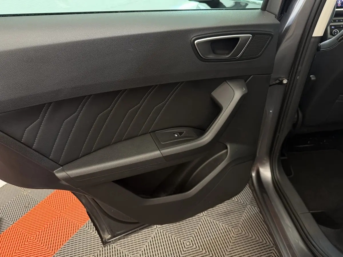 Vue rapprochée de la porte arrière gauche gris clair du SEAT Ateca 2023 avec garniture noire et bouton de fenêtre électrique.