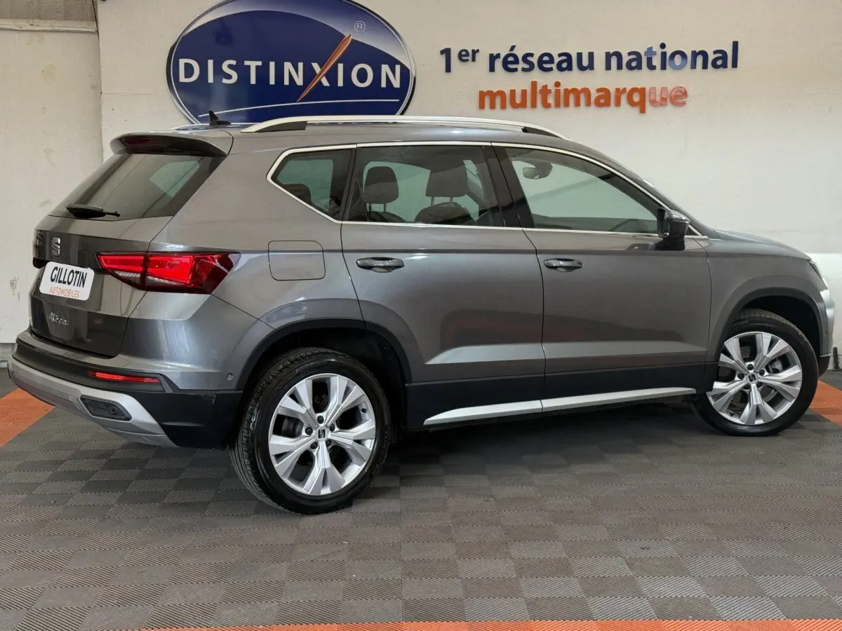 SEAT Ateca gris clair vue de profil côté gauche, SUV compact avec jantes alliage et toit avec barres chromées.