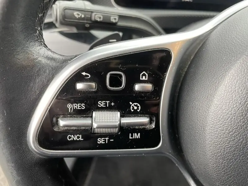Gros plan sur les commandes de régulateur de vitesse au volant d'une Mercedes Classe A 2019 gris foncé métal.
