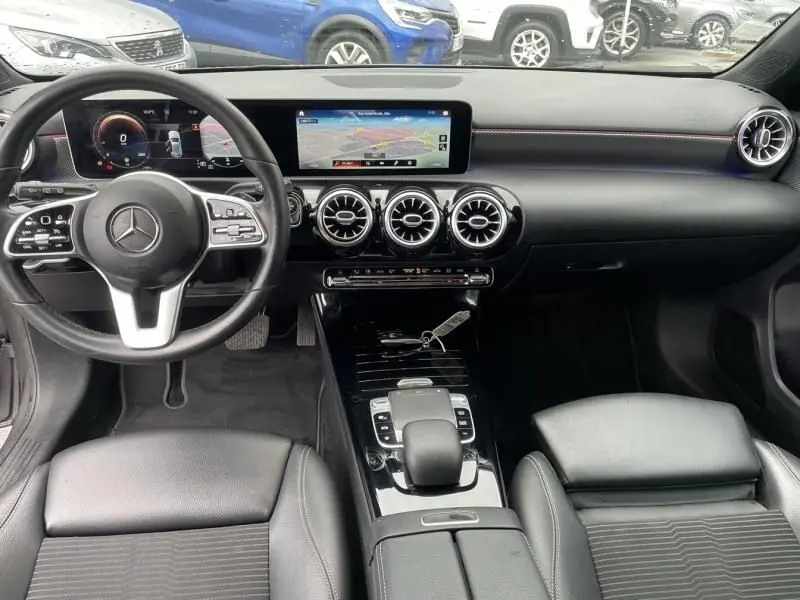 Vue intérieure avant de la Mercedes Classe A 200 Progressive line 2019, tableau de bord noir avec écran large et aérateurs ronds chromés.