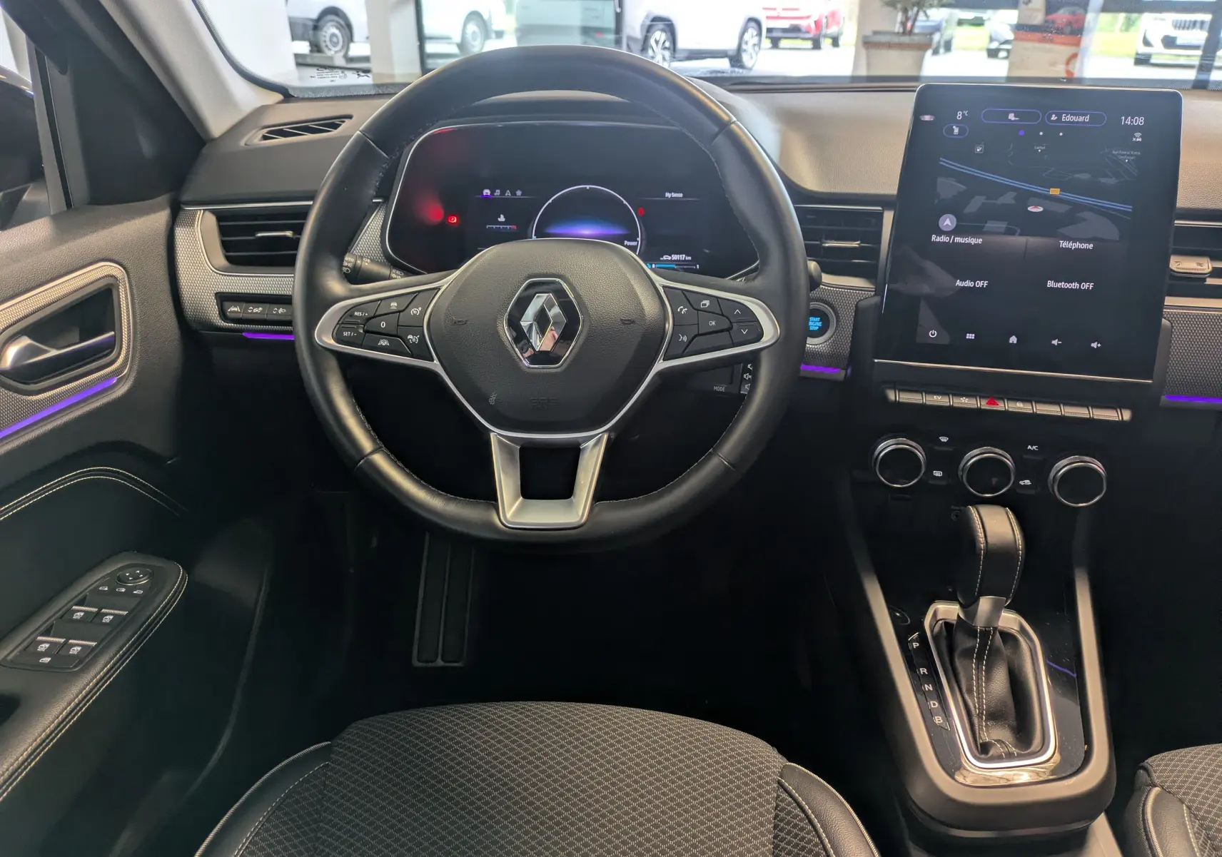 Vue intérieure centrée sur le volant et la console centrale d’une Renault Arkana noire, avec écran tactile et levier de boîte automatique.