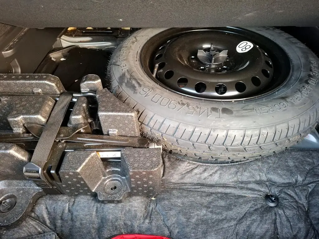 Vue rapprochée de la roue de secours galette noire dans le coffre du Renault Arkana 2023 hybride noir métal.