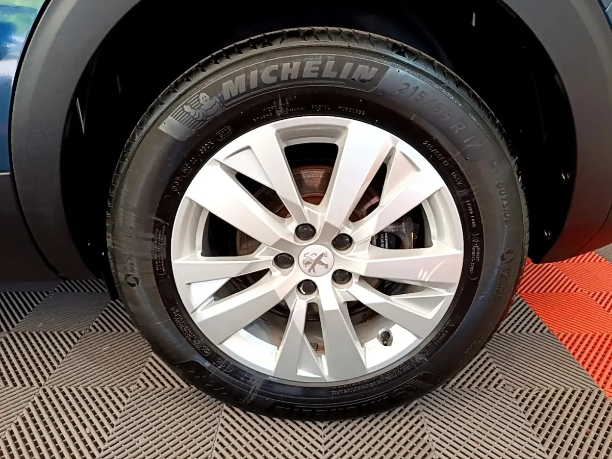 Gros plan sur la roue avant droite d’un Peugeot 5008 bleu avec jante alliage et pneu Michelin.