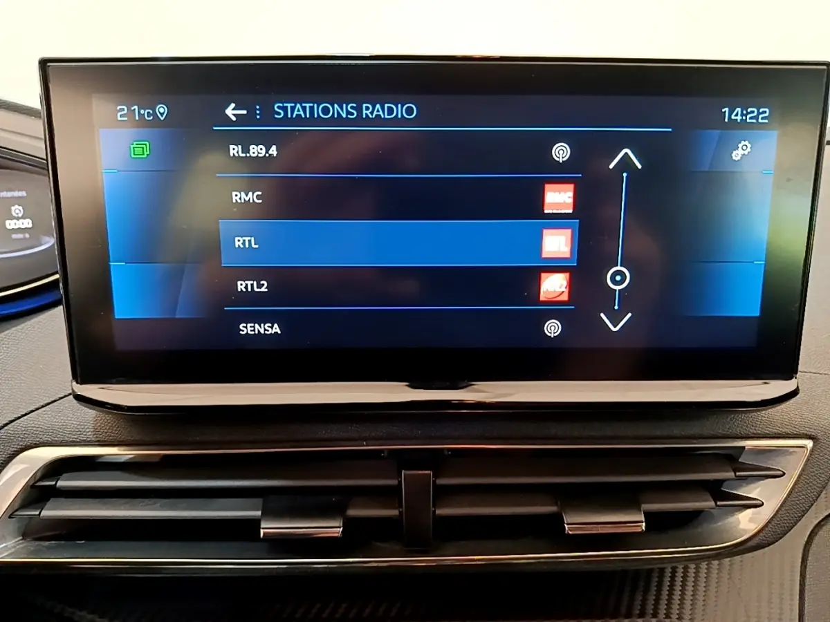 Écran tactile central affichant les stations radio dans l’habitacle d’un Peugeot 5008 bleu, vue de face.