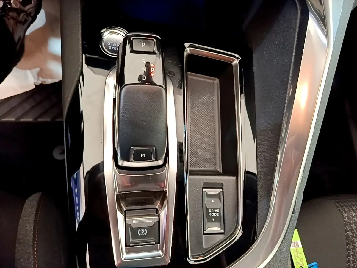 Vue rapprochée de la console centrale noire brillante du Peugeot 5008 avec levier de boîte automatique et bouton Drive Mode.