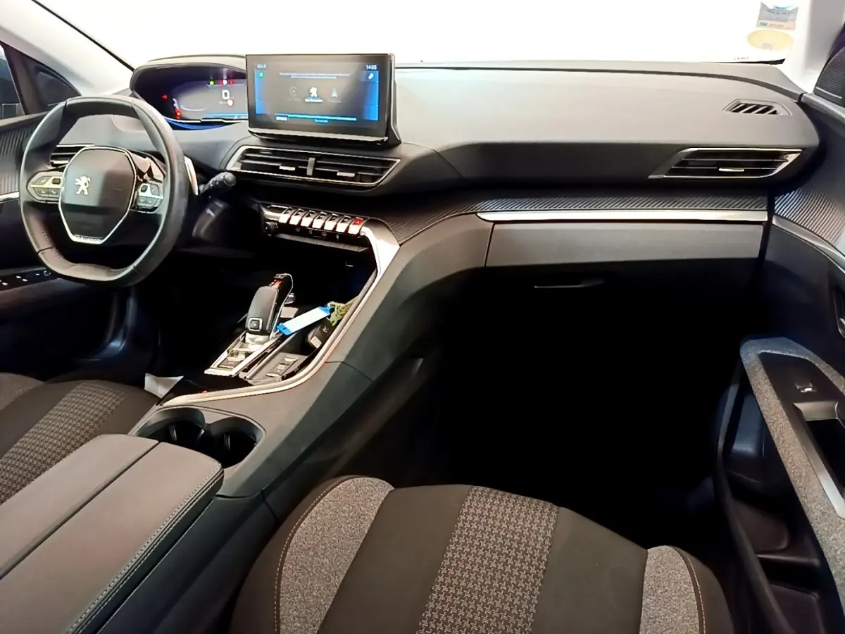 Intérieur du Peugeot 5008 bleu, vue côté conducteur, tableau de bord moderne avec écran tactile central et volant cuir multifonctions.