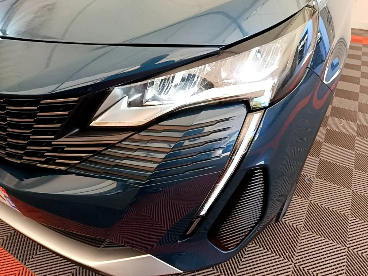 Gros plan sur l'avant droit bleu du Peugeot 5008 2021, mettant en valeur le phare LED et la calandre distinctive.