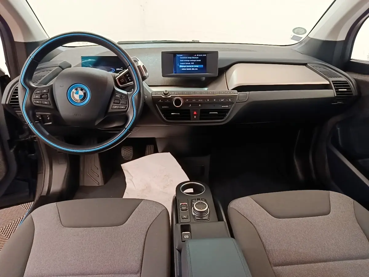 Intérieur avant de BMW i3 120 Ah noir, vue centrée sur le tableau de bord et le volant multifonction avec détails bleus.