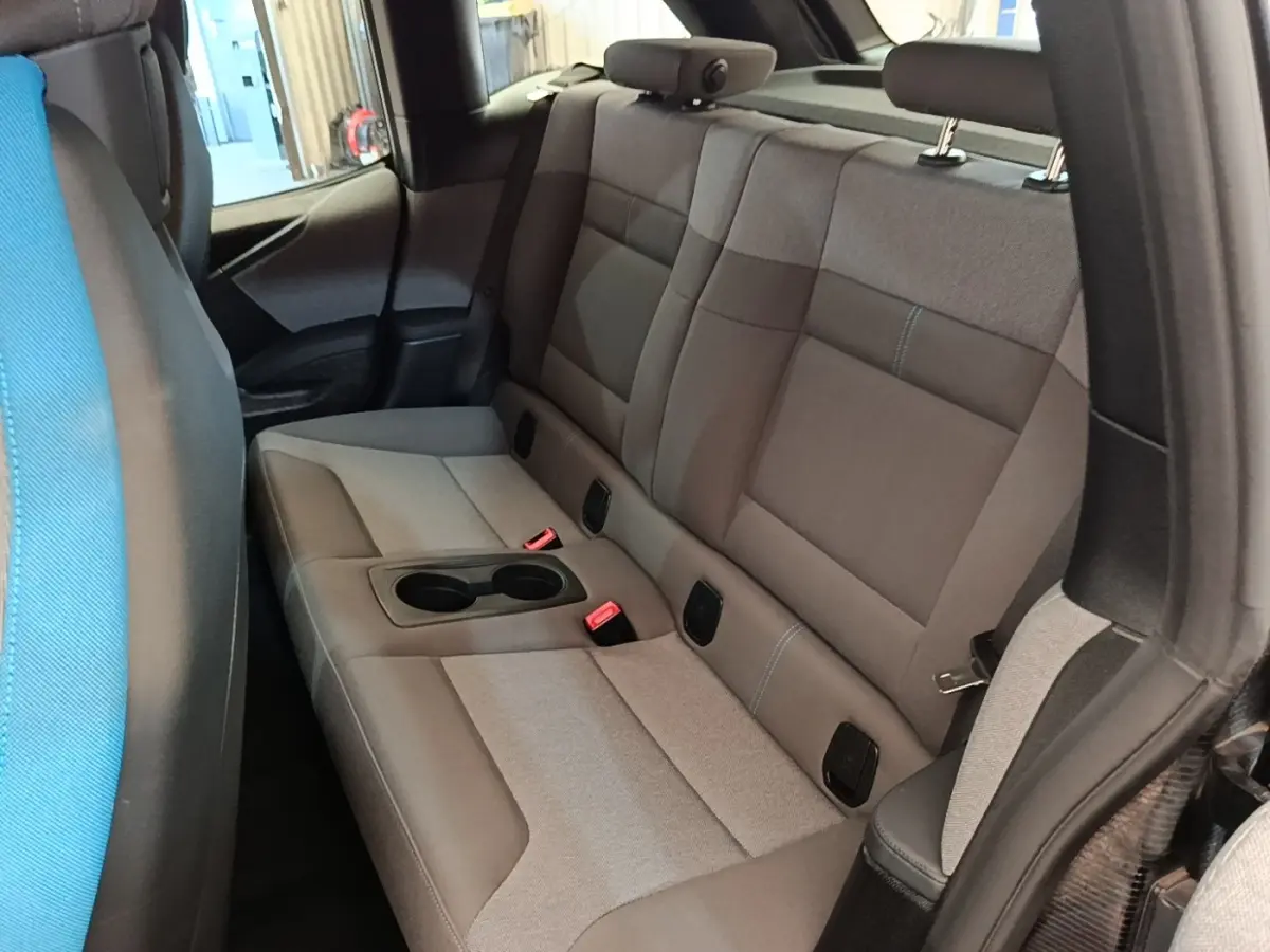 Vue intérieure arrière droite sur la banquette sport grise du BMW i3 120 Ah Atelier avec accoudoir central et porte-gobelets.