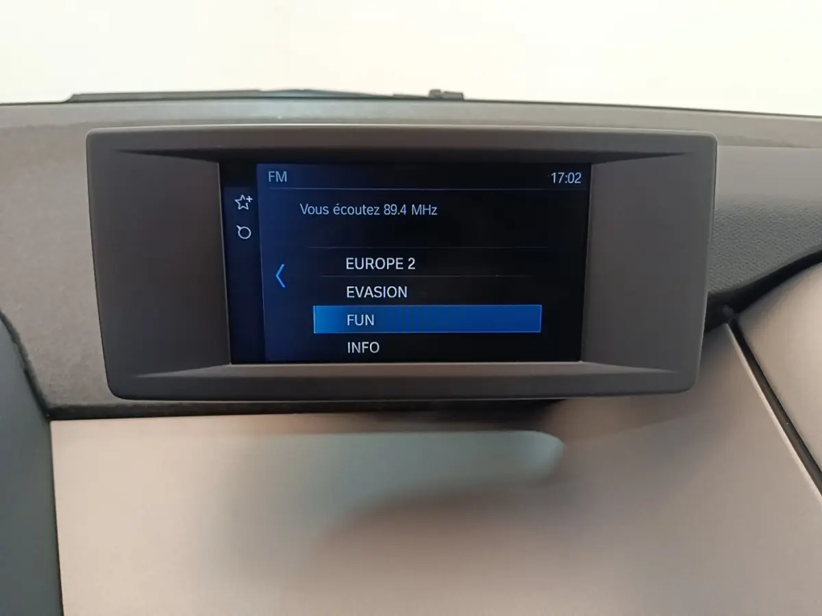 Écran central du tableau de bord de la BMW i3 noire 120 Ah Atelier, affichant les stations radio FM.