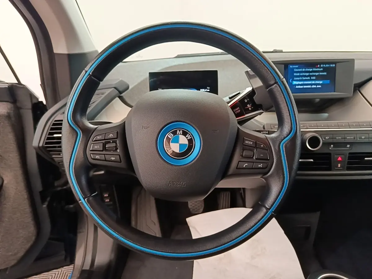 Vue intérieure centrée sur le volant noir avec liseré bleu de la BMW i3 120 Ah Atelier de 2020.