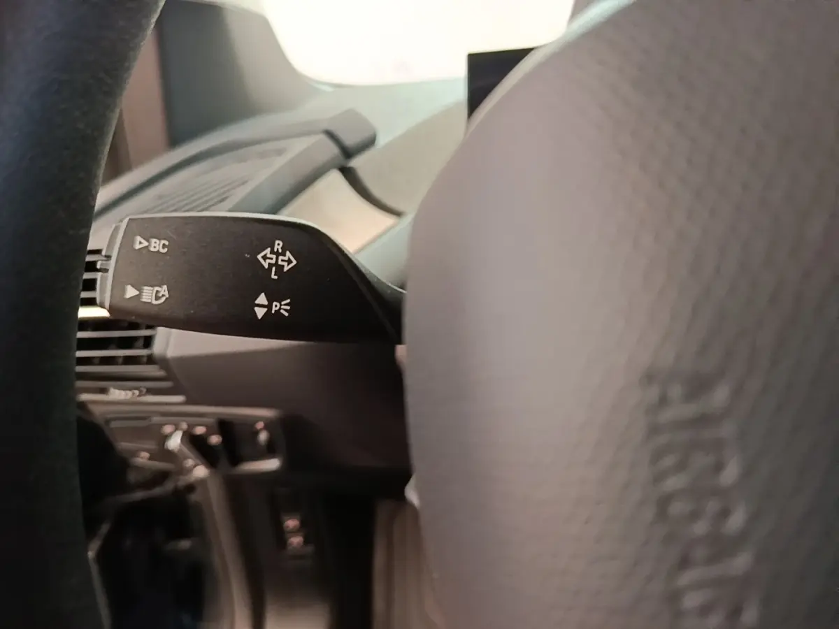 Gros plan sur la manette de clignotant à gauche du volant dans l'habitacle d'une BMW i3 noire 2020.
