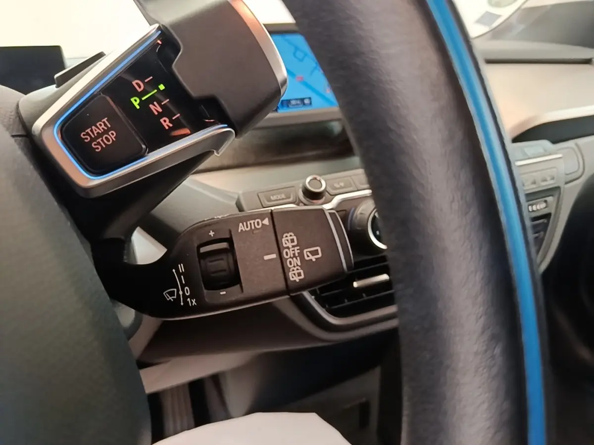 Gros plan sur la commande de boîte automatique et bouton start/stop à gauche du volant cuir noir d'une BMW i3 120 Ah Atelier 2020.