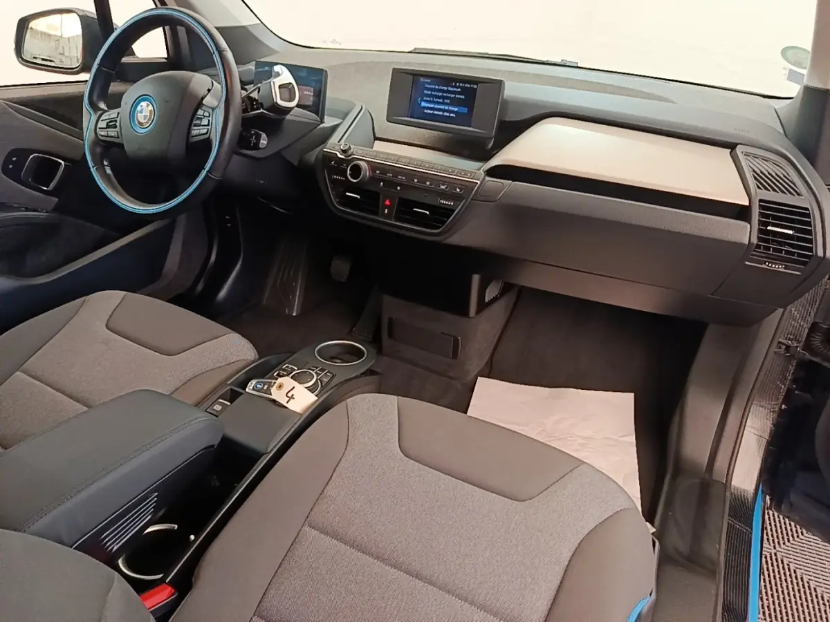 Vue intérieure côté conducteur de la BMW i3 120 Ah noire, avec tableau de bord digital et volant cuir multifonctions.